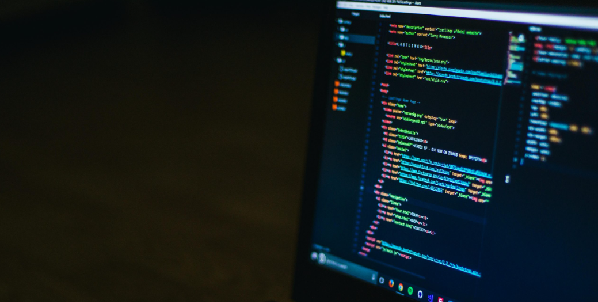 A close-up of a computer screen displaying colorful lines of code against a dark background. The code appears to be written in a text editor, with syntax highlighting visible for various programming elements. The room is dimly lit.